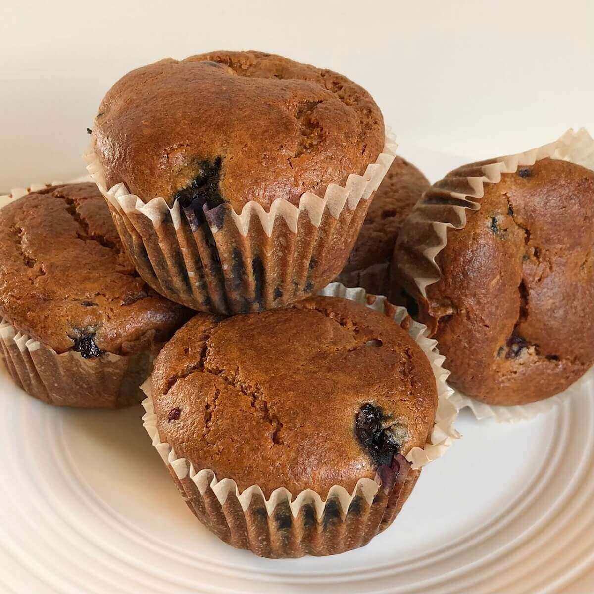 Five muffins displayed on a plate.