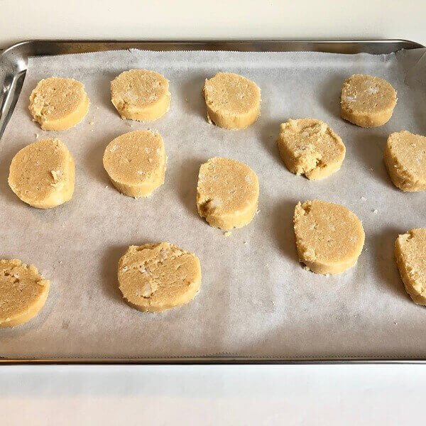 Raw cookie batter in slices on a sheet pan.