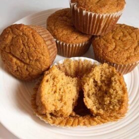 Five muffins on a white plate.