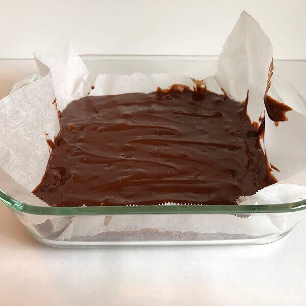 Raw brownie batter in a glass baking dish.