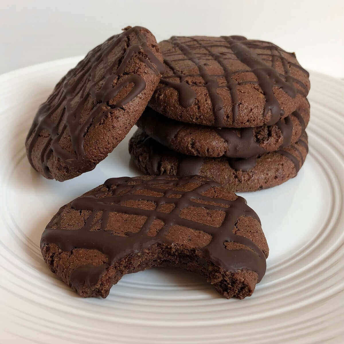 Buckwheat flour cookies on a white plate with a bite missing from one of them.