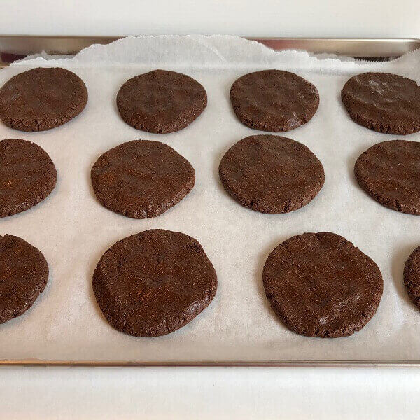 Raw cookie dough pressed into circles on a sheet pan.