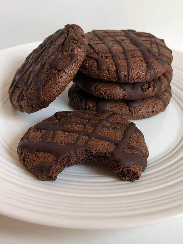 Five cookies on a plate with a bite missing from one.