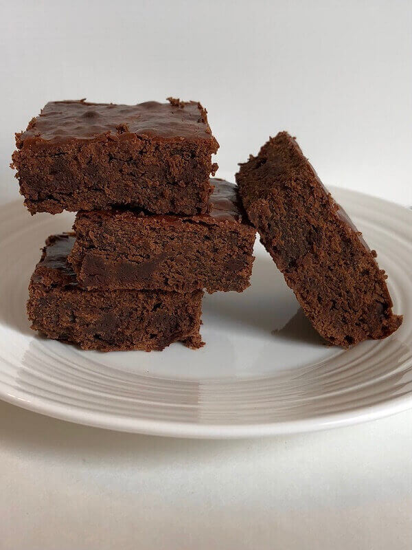 Brownies stacked on a white plate.