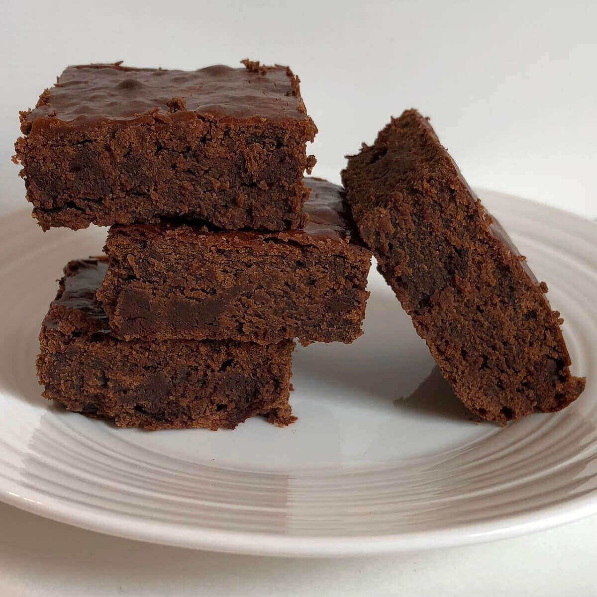 Four chickpea flour brownies on a plate.