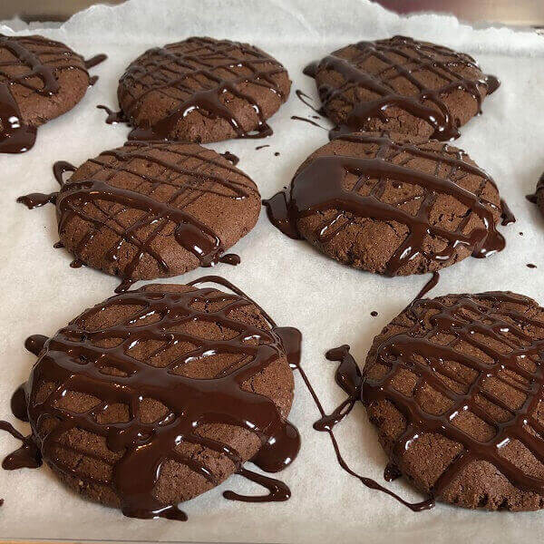 Cookies drizzled with chocolate on a sheet pan.
