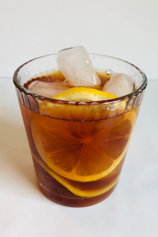 Iced tea in a glass with ice cubes and lemon slices.