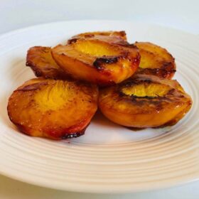 Caramelized peaches on a white plate.