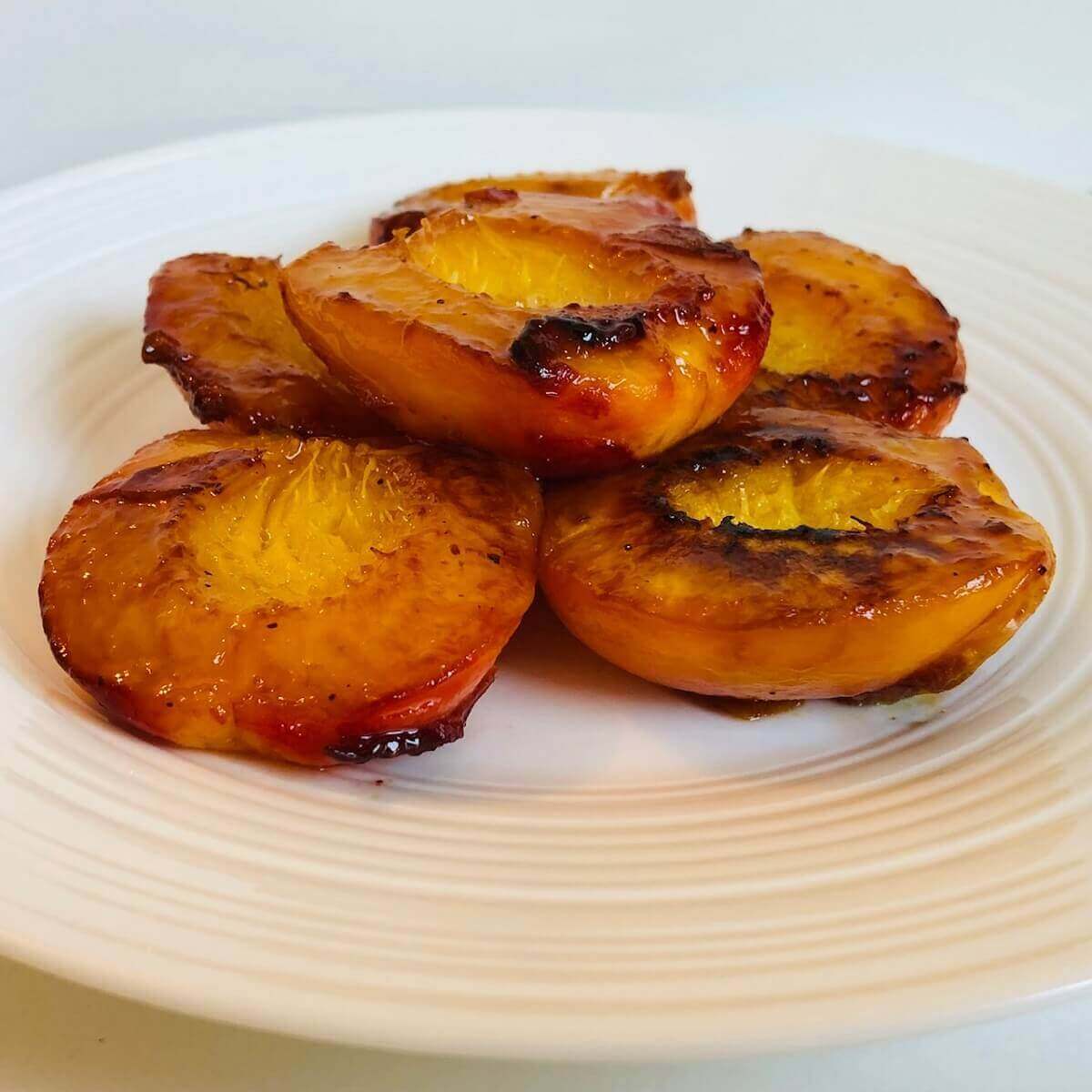 Cooked peaches on a white plate.