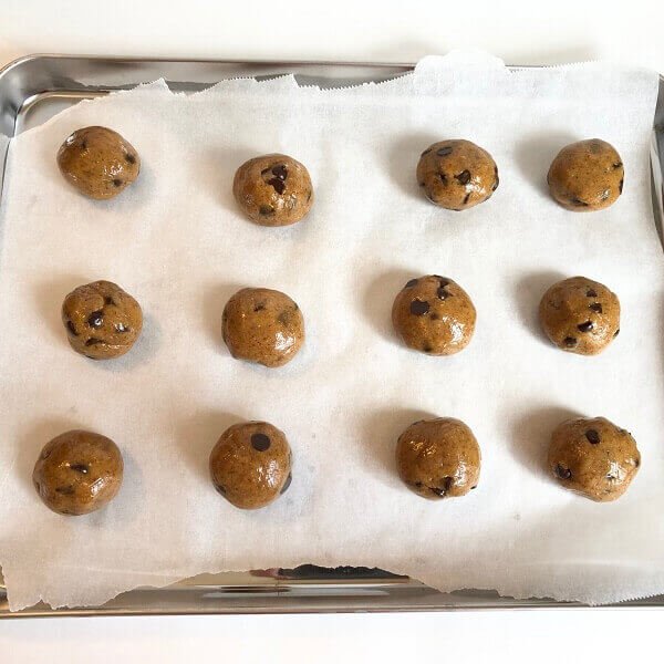 Twelve cookie dough balls on a baking tray.