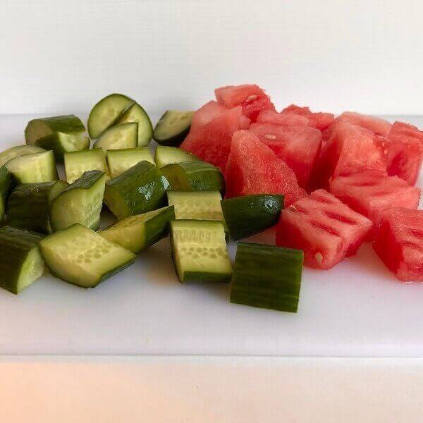 Chopped watermelon and cucumber on a cutting board.