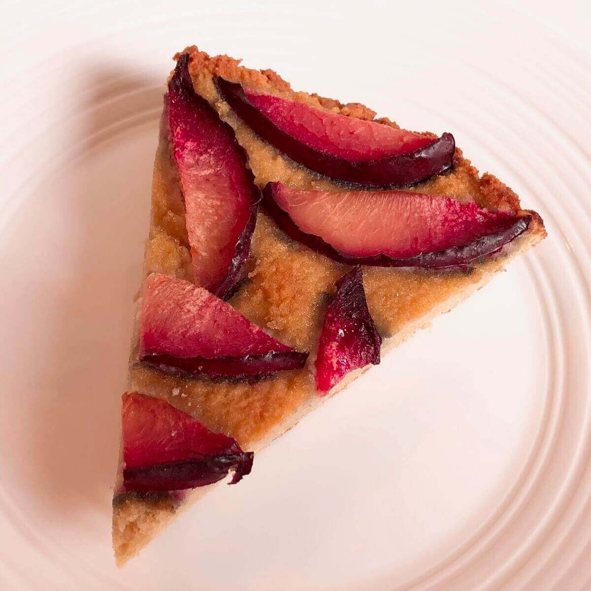 A piece of gluten-free plum cake with sliced plums on top.