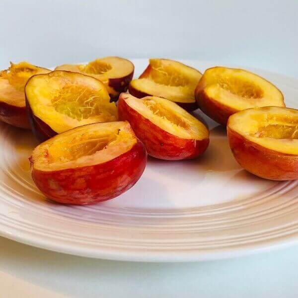 Raw fresh peach halves on a plate.