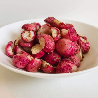 Garlic roasted radishes in a white bowl.