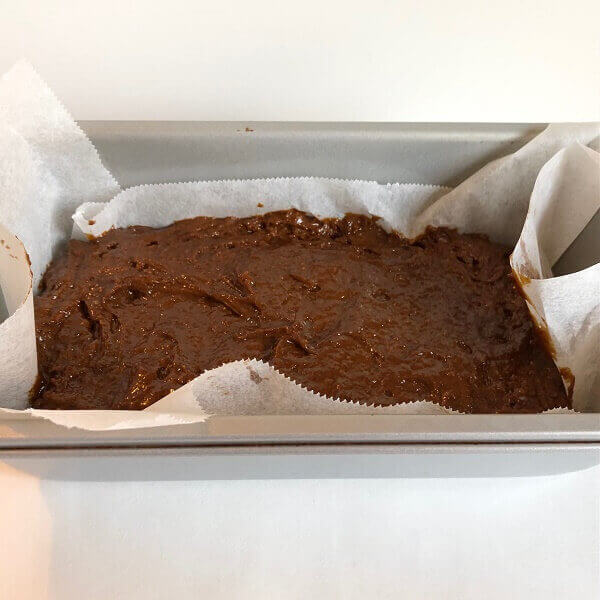 Raw batter in a paper lined loaf pan.