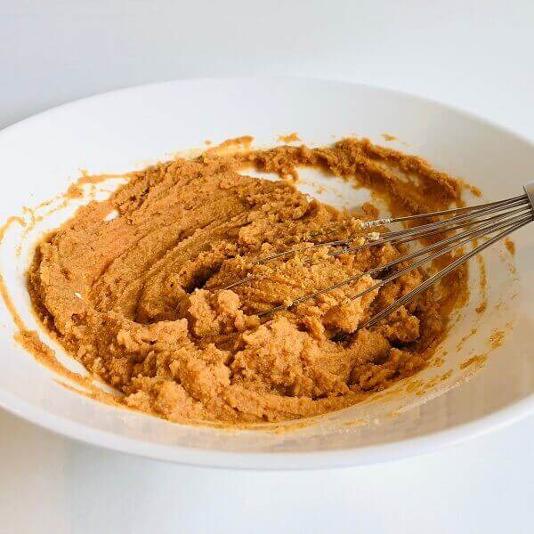 Raw pumpkin bread batter in a mixing bowl with a whisk.