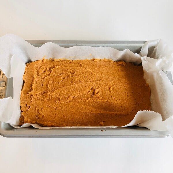 Pumpkin loaf batter in a parchment paper lined pan.
