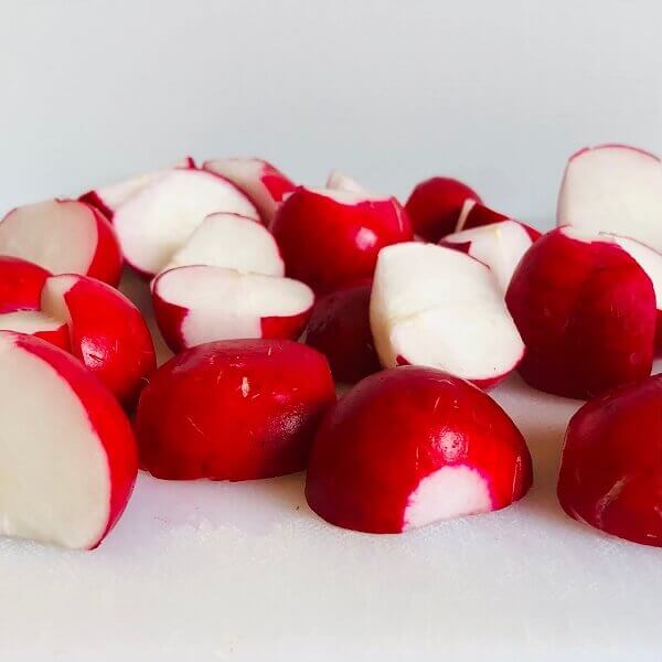 Radishes cut in half on a cutting board.