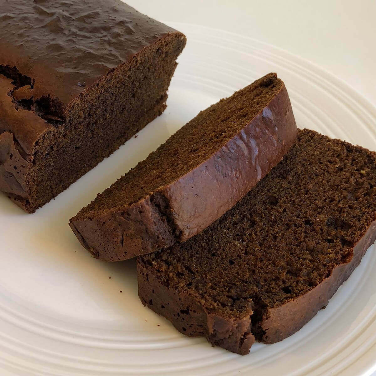 Gluten-free gingerbread cake with two slices cut on a plate.