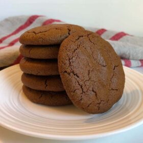 Vegan Molasses cookies stacked on a plate with a red striped dish cloth in the background.