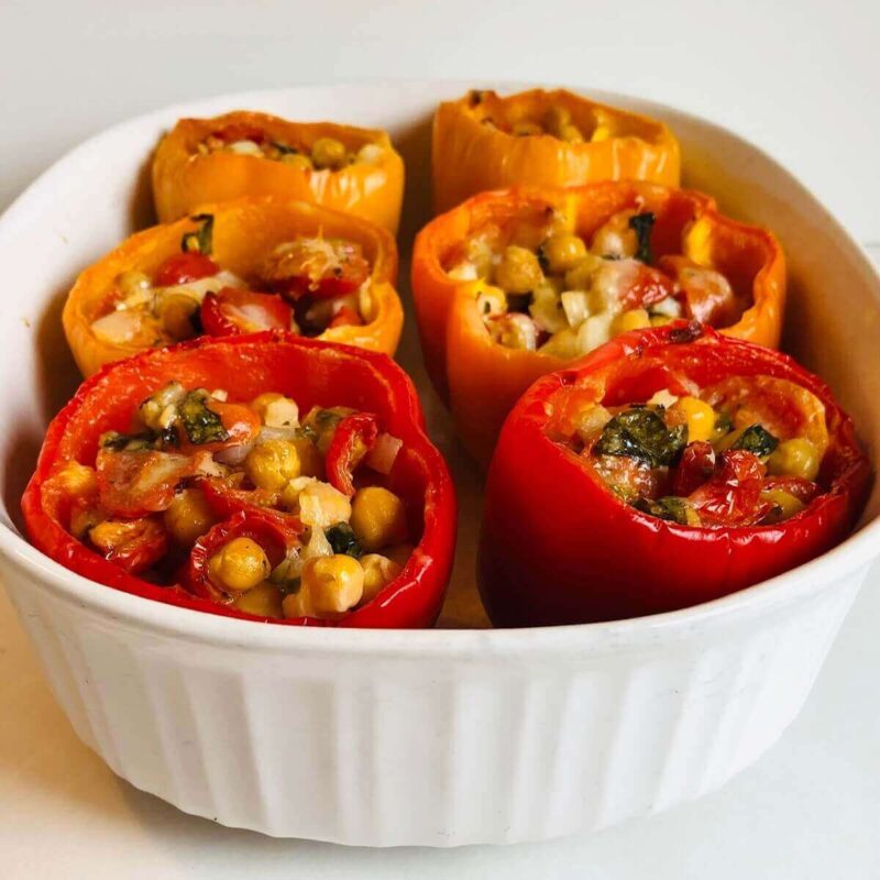 Six cooked stuffed peppers in a casserole dish.