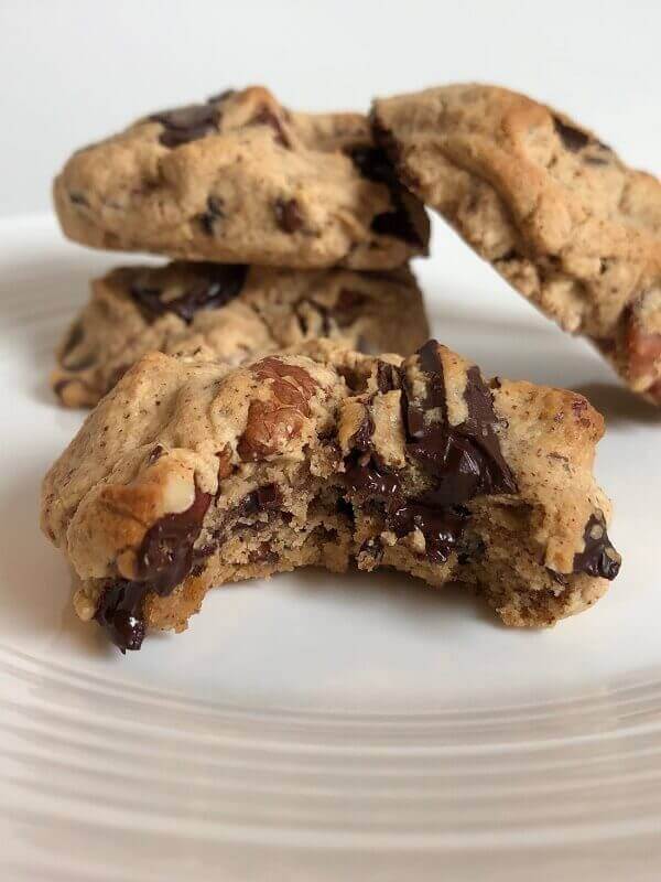 A thick cookie with a bite missing and more cookies in the background.