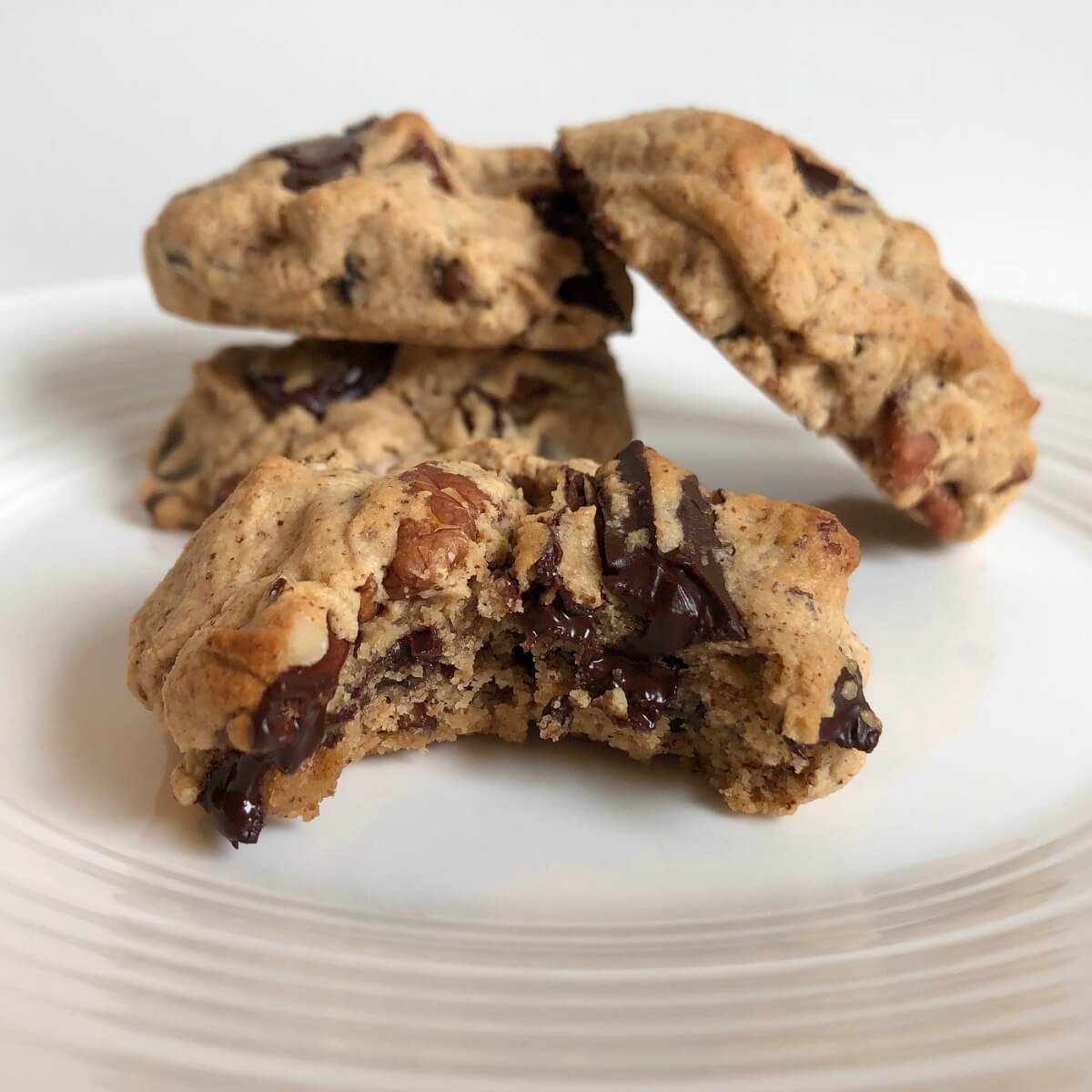 Four thick vegan pecan cookies on a plate.