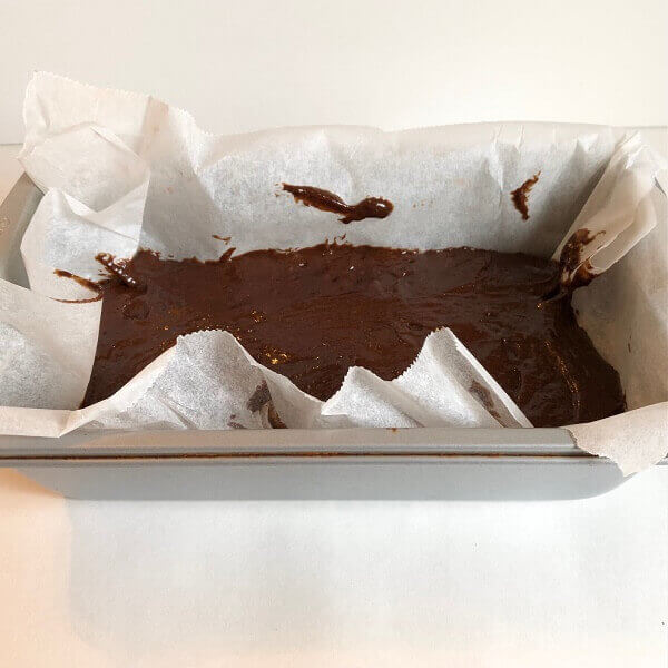 Bread batter in a parchment paper lined loaf pan.