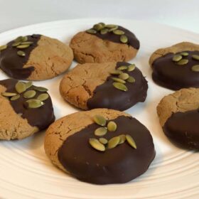 Cookies dipped in chocolate with pumpkin seeds sprinkled on top.