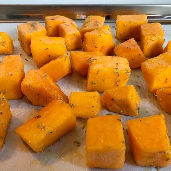 Raw butternut squash cubes on sheet pan.