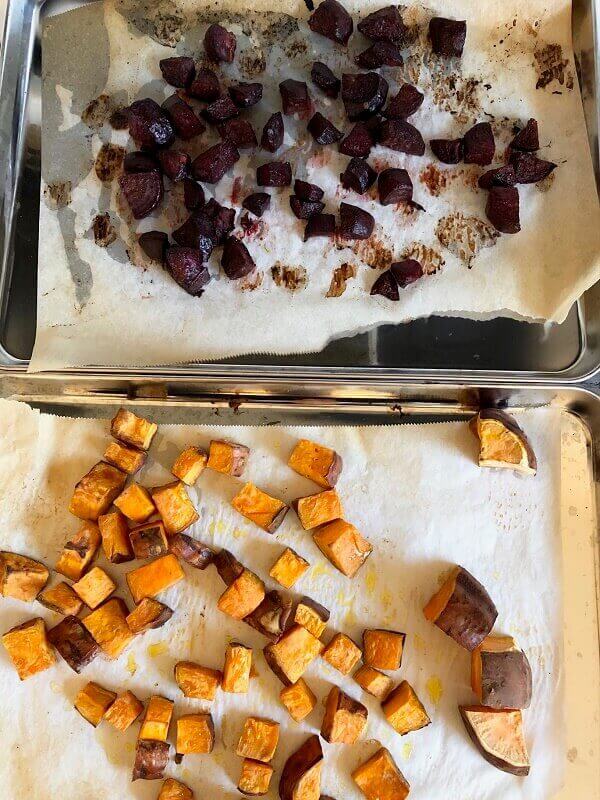 Two sheet pans with roasted beets and sweet potatoes.