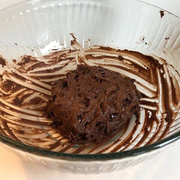 Chocolate cookie dough in a large glass bowl.