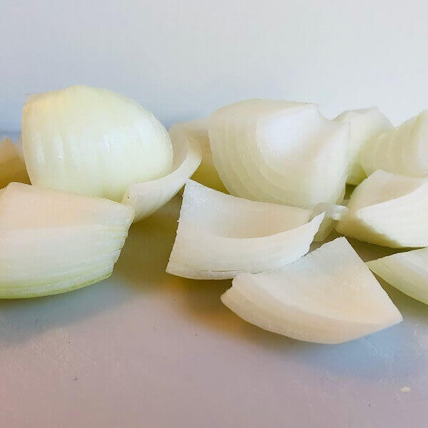 Raw chopped onions on a white cutting board.