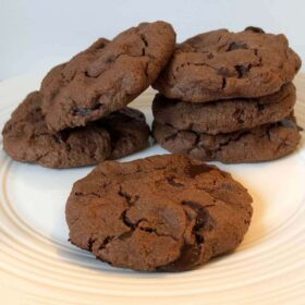 Six chocolate cookies on a white plate.