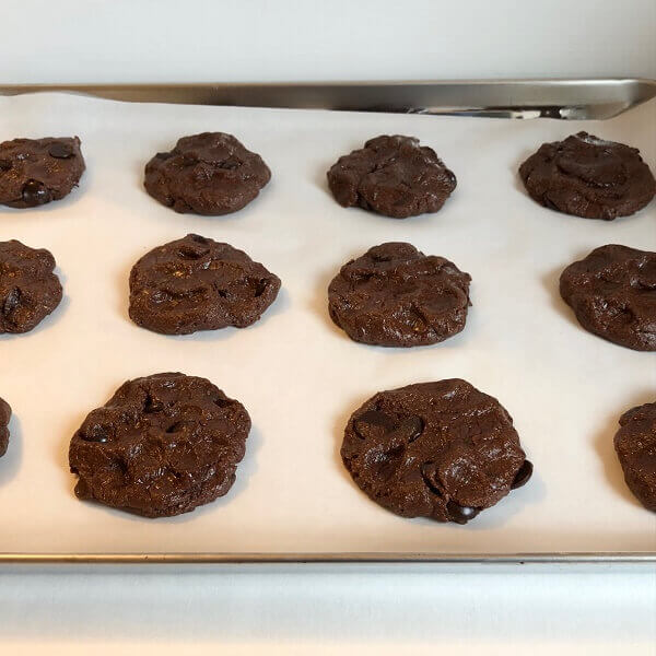 Raw chocolate cookies on a sheet pan.