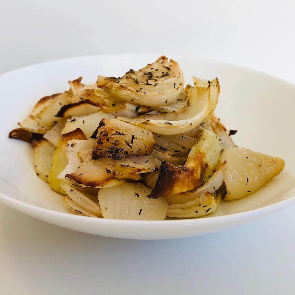 Slow roasted onions in a white serving bowl.