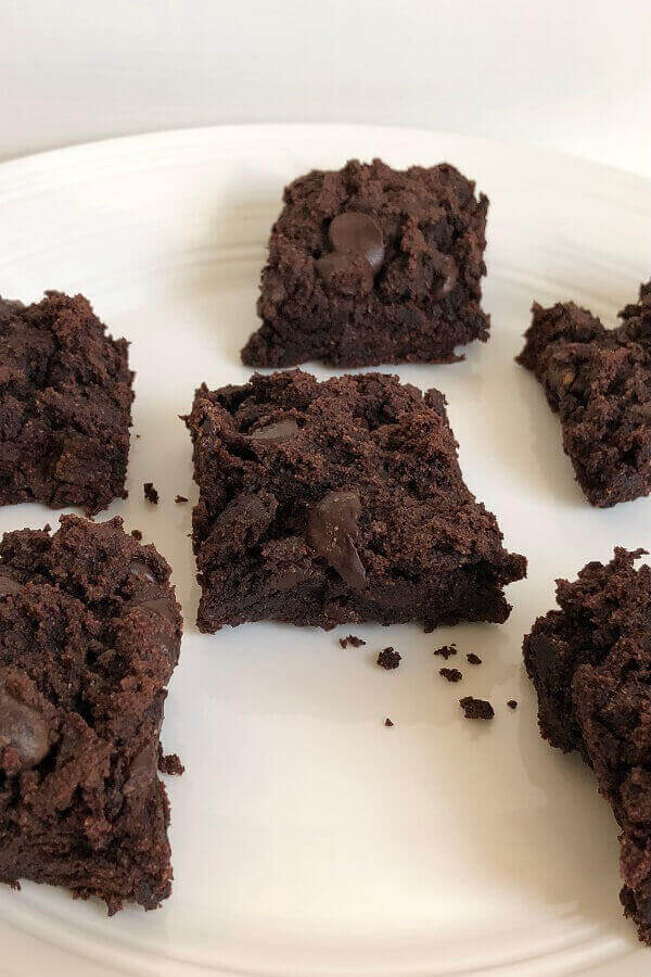 Brownies on a white plate with crumbs spilled.