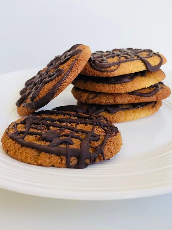 Chocolate drizzled cookies on a white plate.