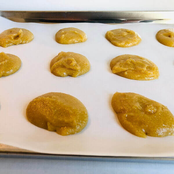Blobs of cookie dough on a sheet pan lined with parchment paper.