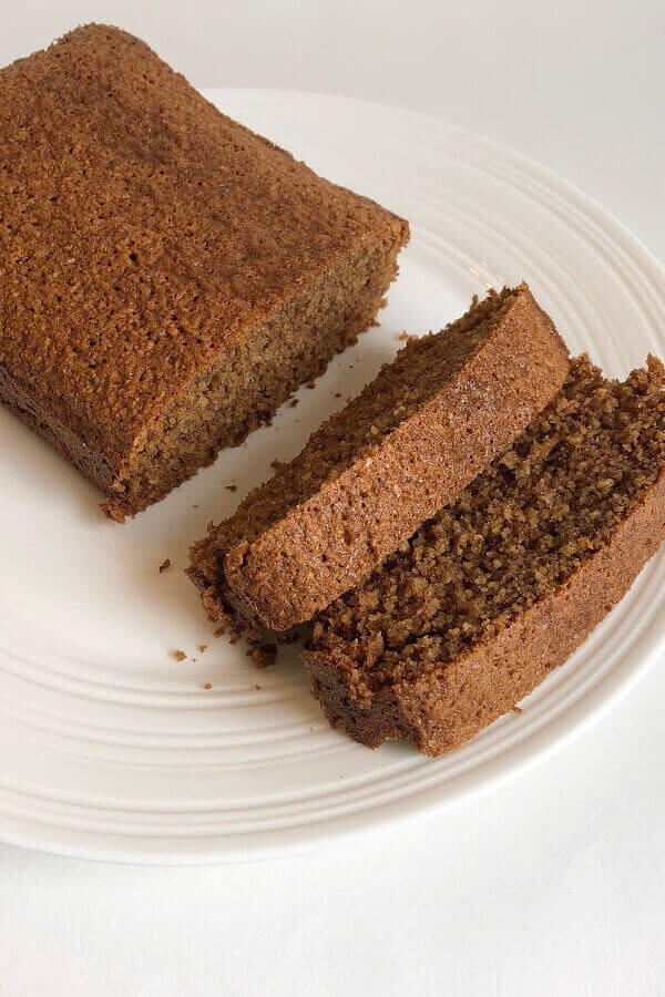 A loaf cake sliced on a white plate.