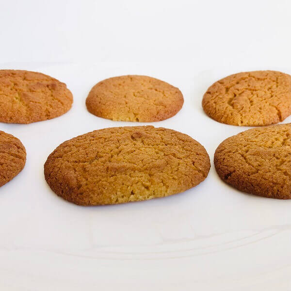 Golden brown cookies cooling on a white plate.