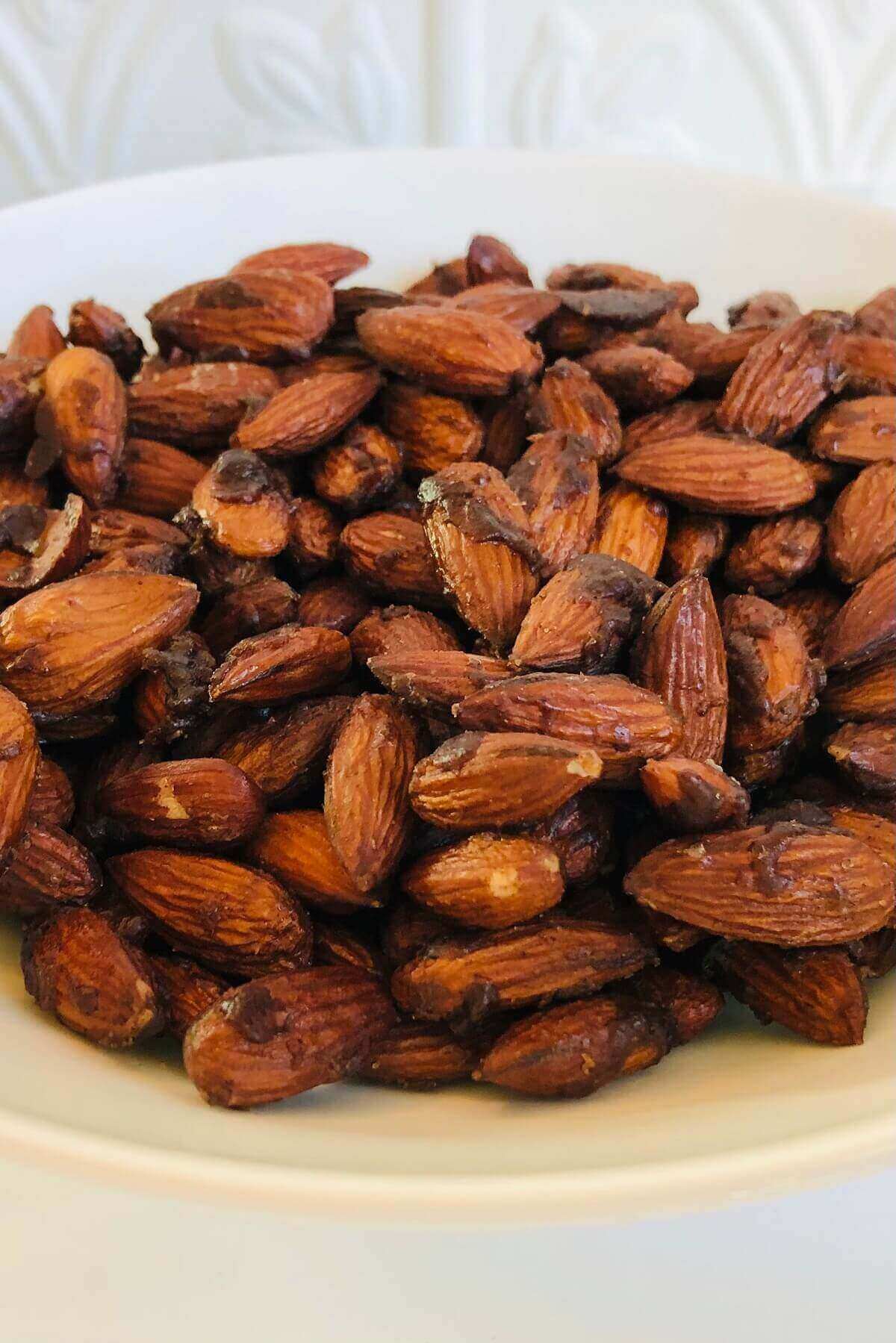 Roasted almonds in a white bowl.