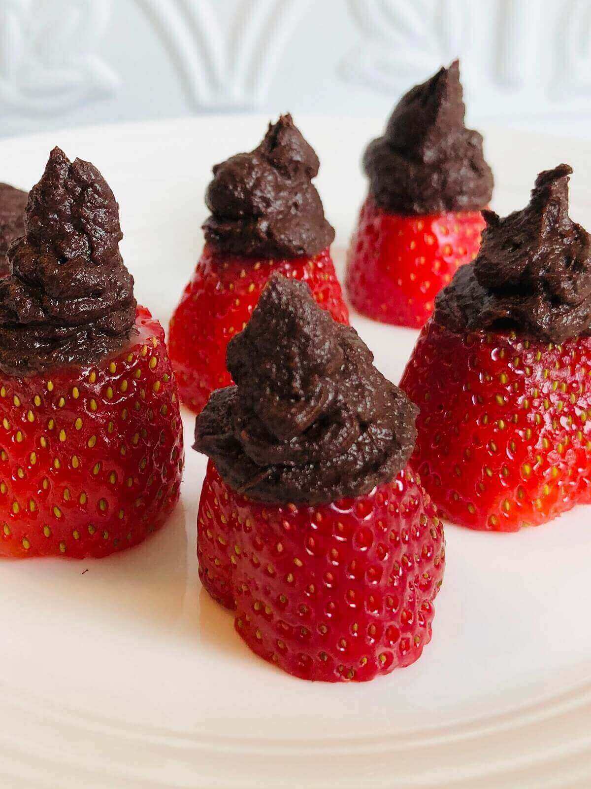 Strawberries stuffed with chocolate filling on a plate.
