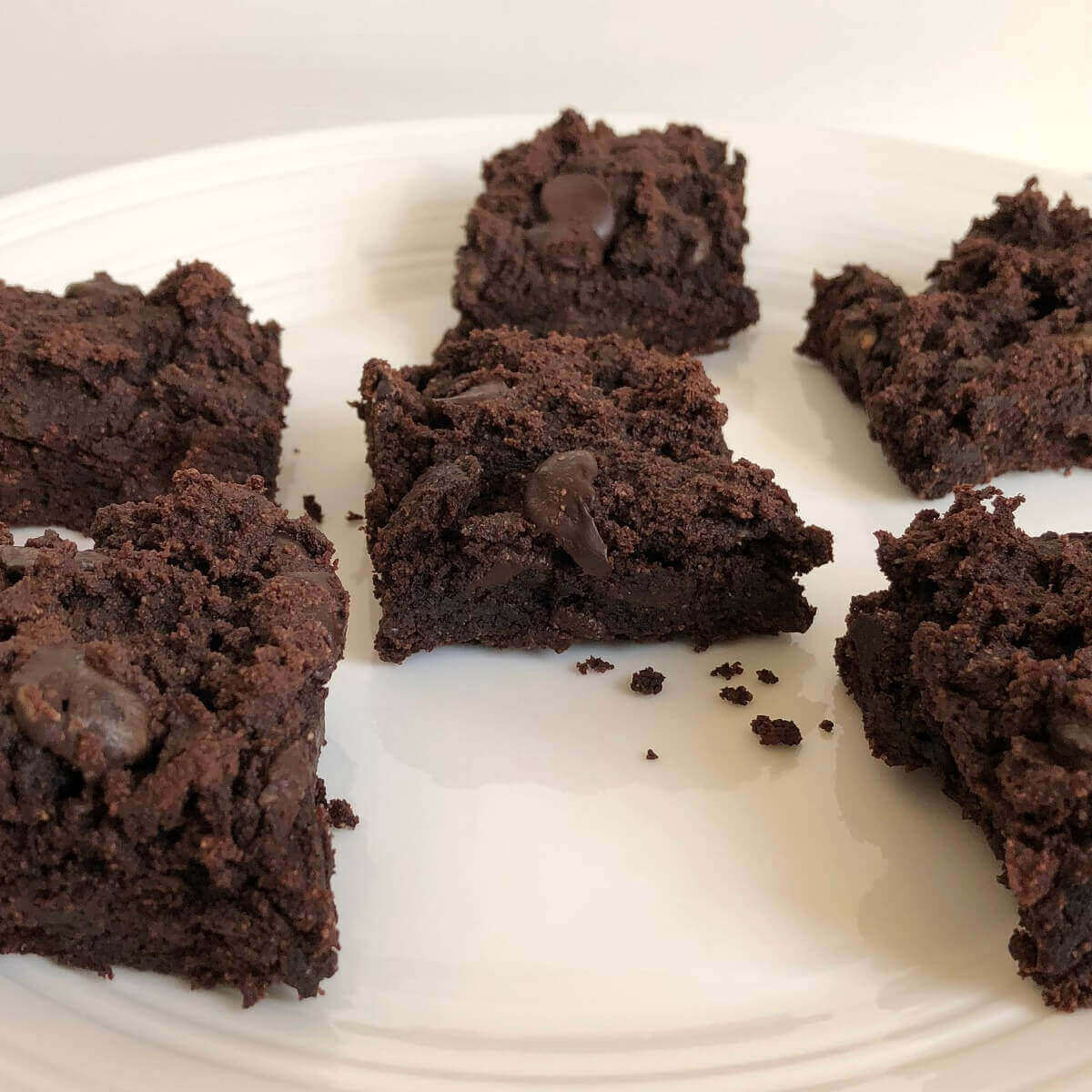 Six coconut flour brownies on a plate.