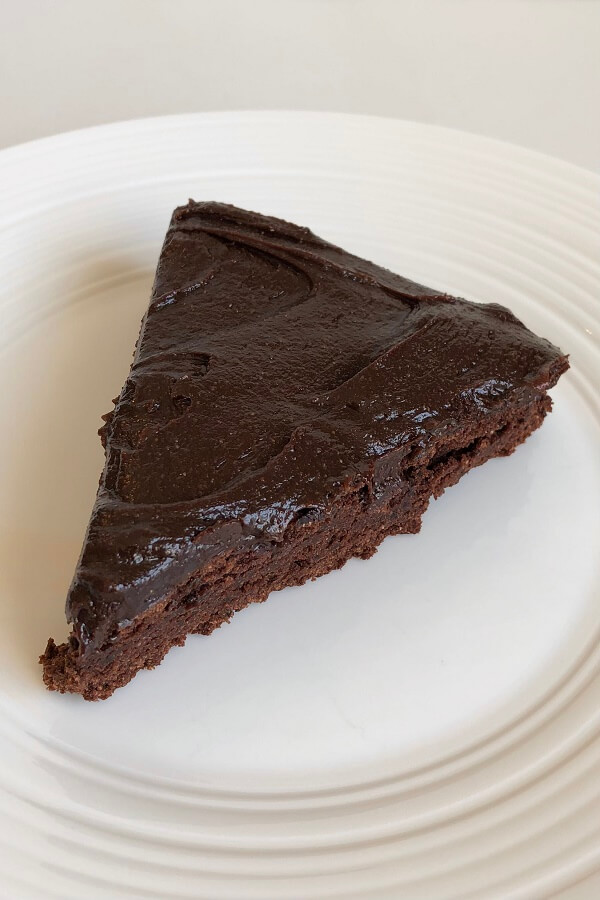 A slice of cake with icing on a white plate.