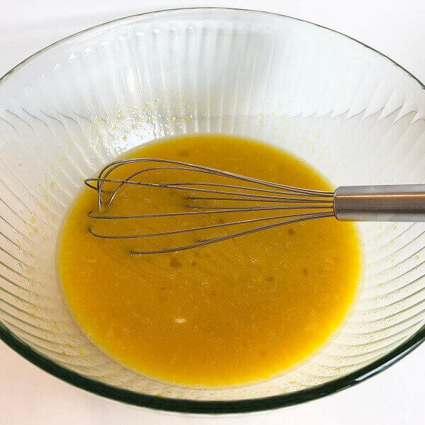 Ingredients in a large glass bowl with a whisk.