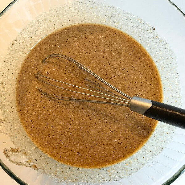 Banana bread batter being stirred by a whisk.