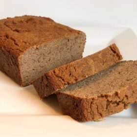 A loaf of coconut flour banana bread with two slice cut.