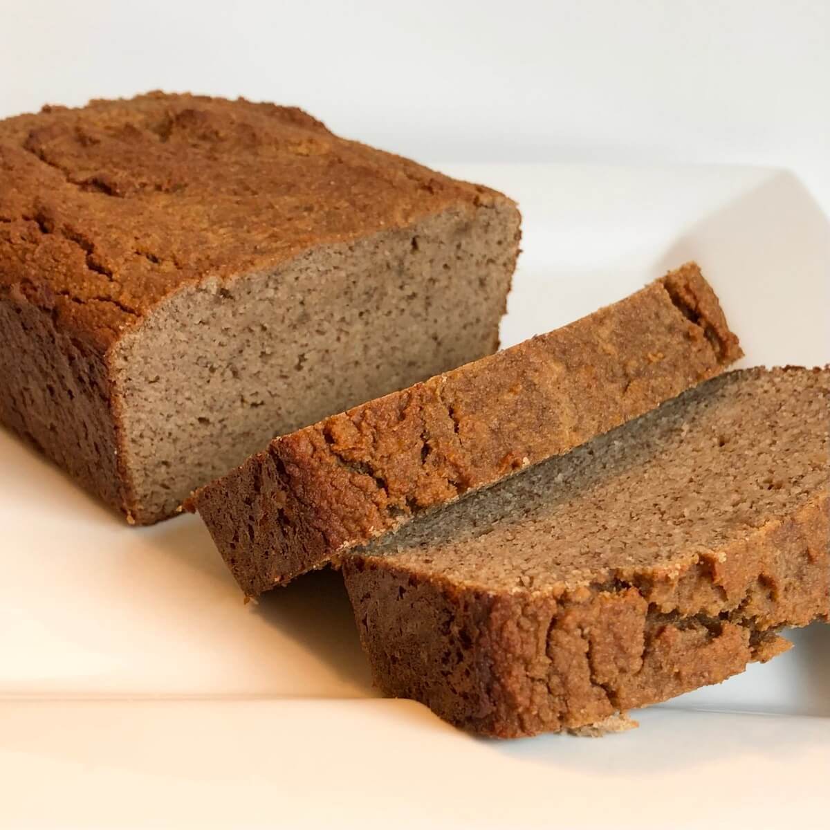 A loaf of grain free banana bread with two slice cut.
