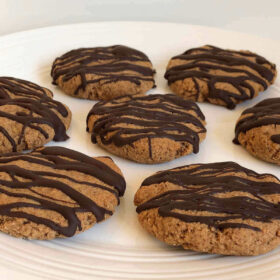 Seven coconut flour banana cookies on a white plate.